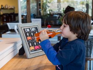 Young kombucha fan taking a sip at the kombucha mini bar located inside Ferm Farm. (Grant Geipel)